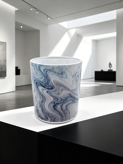 Empty blue marble fluid ink candle jar styled on a black and white pedestal in a modern art gallery setting