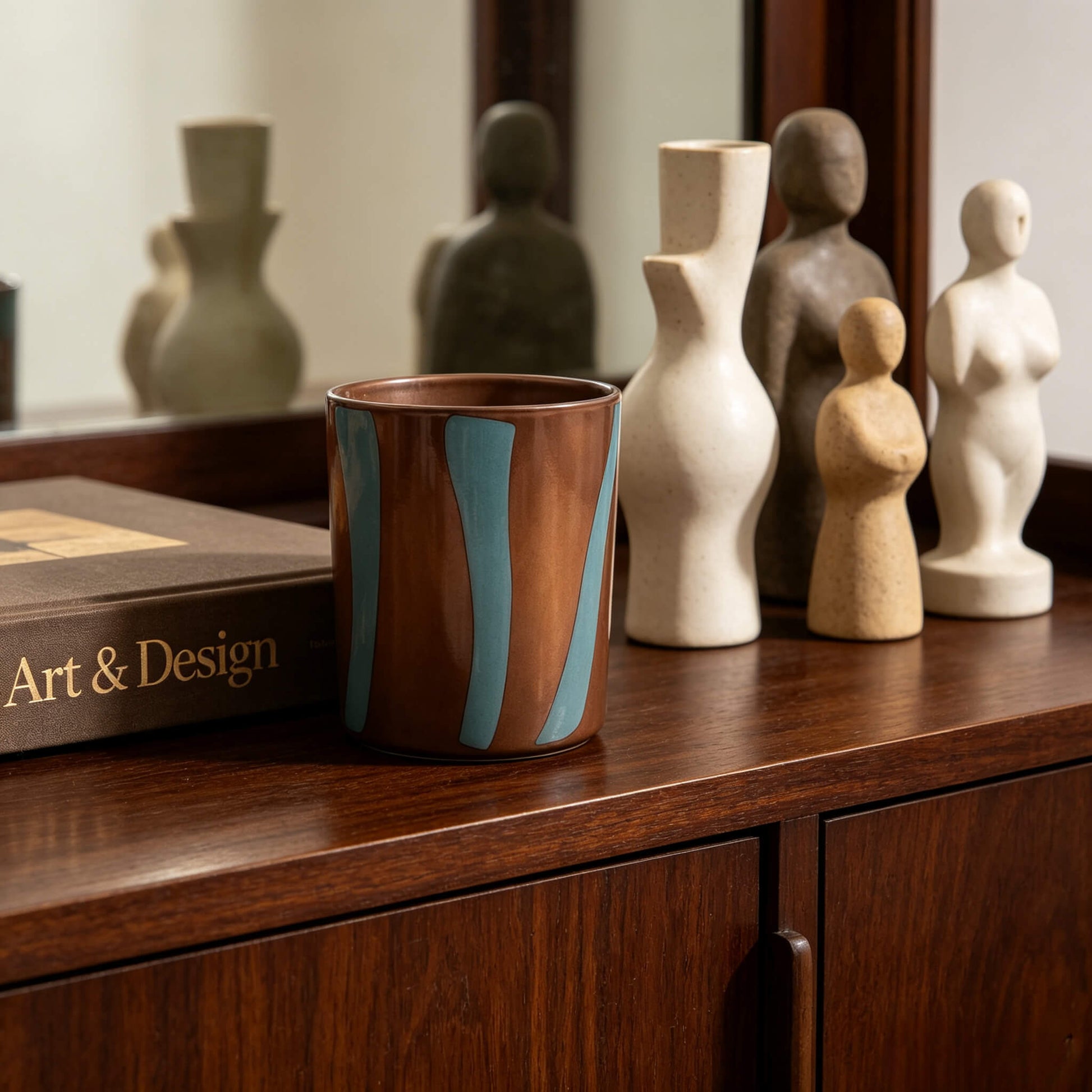 Modern color block candle jar in terracotta and green on a dark wood cabinet for nature inspired scent lines