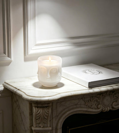 Lit matte white 3D face candle jar glowing softly on a Parisian marble mantel for luxury home fragrance
