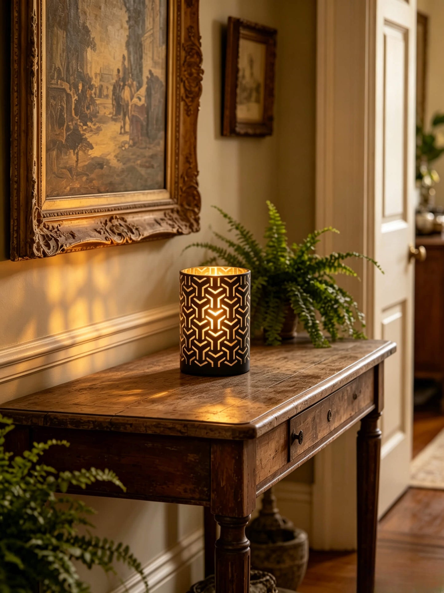 Lit labyrinth cut out glass candle vessel glowing on a vintage wood console table in a luxury entryway