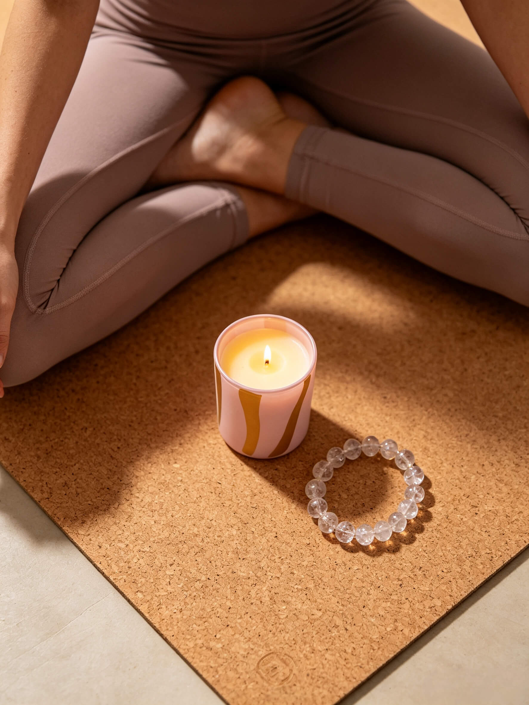 Top down view of empty dusty pink and yellow striped glass candle vessel with cork texture styling