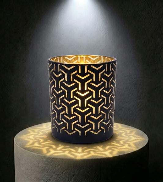 Wholesale matte black and gold labyrinth cut out candle vessel 8 oz casting intricate geometric shadows under spotlight