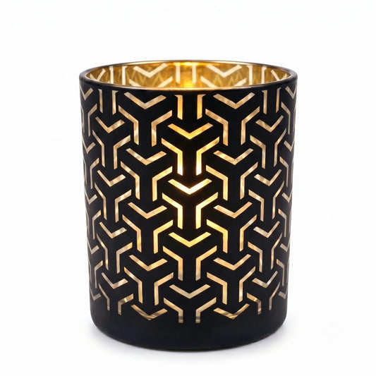 Wholesale matte black and gold labyrinth cut out candle vessel 8 oz casting intricate geometric shadows under spotlight